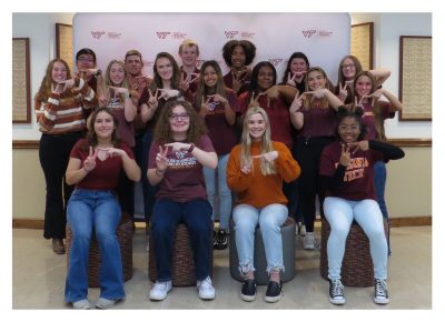 The 2023-2024 Student Ambassador Team as a group doing "VT" with their hands in the lobby of Litton-Reaves Hall.