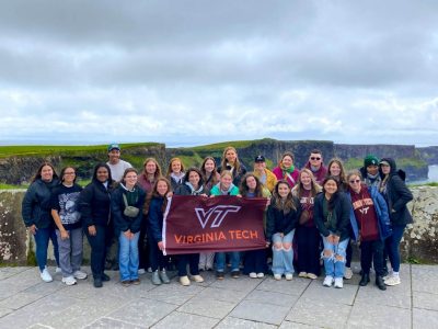 Group of School of Animal Sciences students at the Cliffs of Moher in Ireland with a Virginia Tech flag.