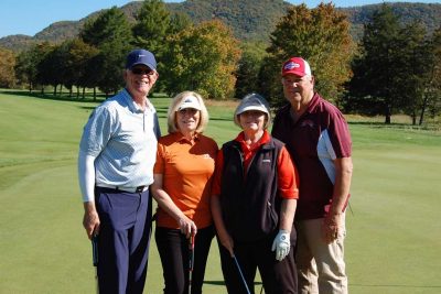 Team Cow Manager, standing together with their golf clubs, facing the camera on the golf course.