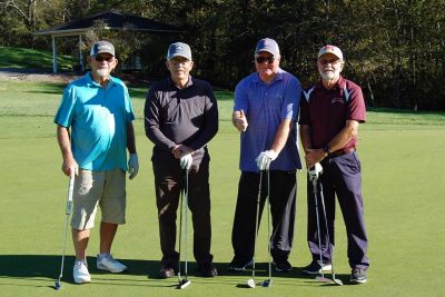 Team Sheets Enterprises standing together with their golf clubs and facing the camera on the golf course.