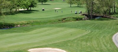 Golfers playing in the distance. Golf carts, sandtrap and bridge crossing a small stream at the Blacksburg Country Club.