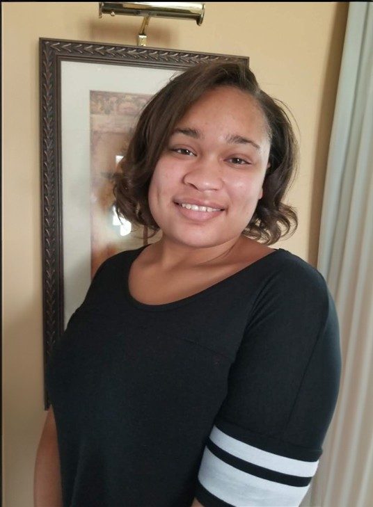 Black woman whith medium short hair wearing a black shirt smiling toward the camera.