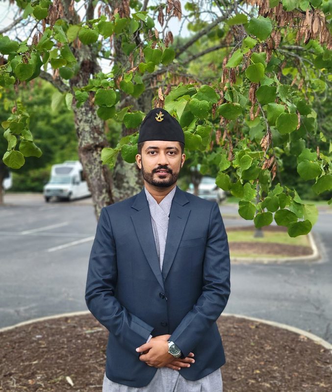 Young man standing in front of a tree.