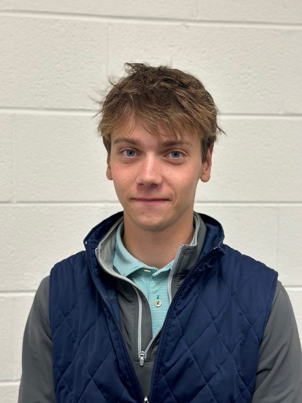 Young man looking toward the camera. Block wall in the background.