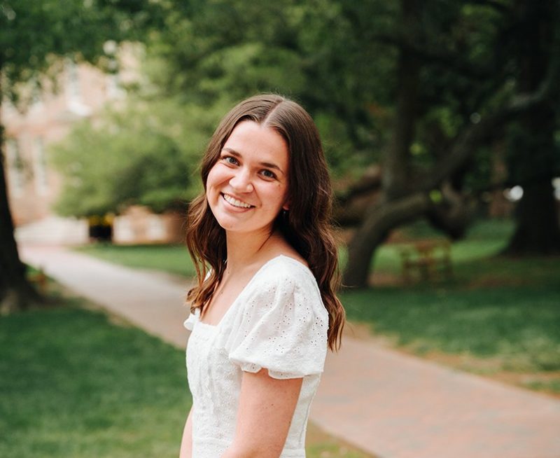 Photo of Grace Phillips outdoors. Walking path and trees in the background.