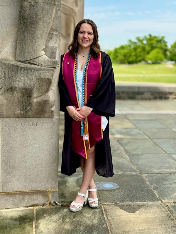 Young woman with should length brown hair wearing graduation regalia.