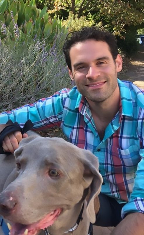 Smiling young man with a gray dog.