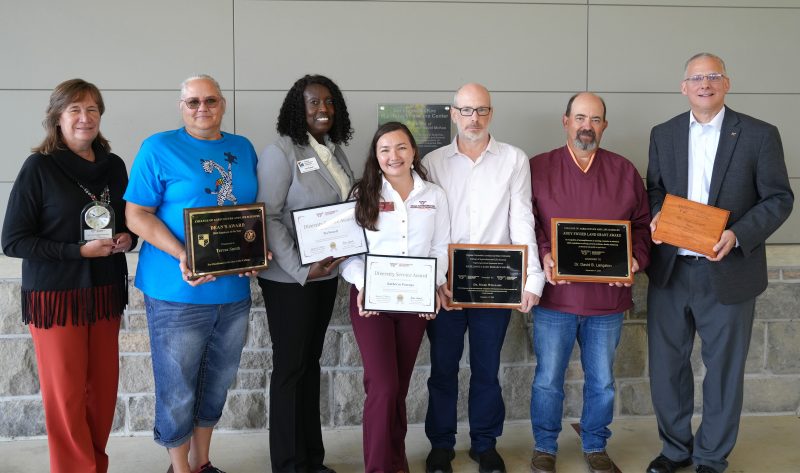 A group of people holding award plaques.