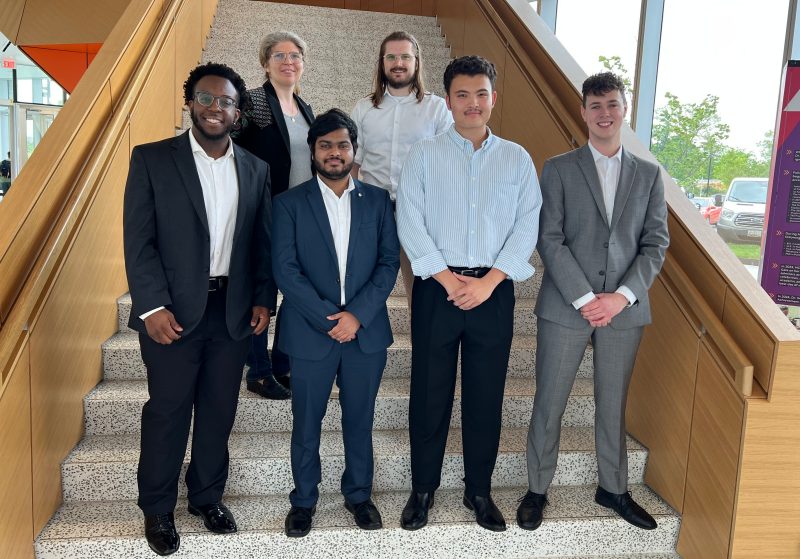 six people stand in two rows on a marble and wood staircase