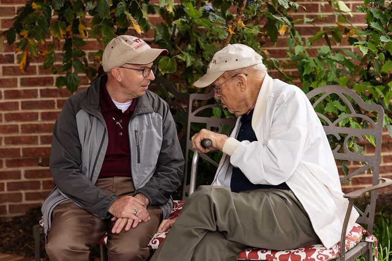 Dave Winston and Dr. Carl Polan, Professor Emeritus,  in conversation on a bench. 2023.