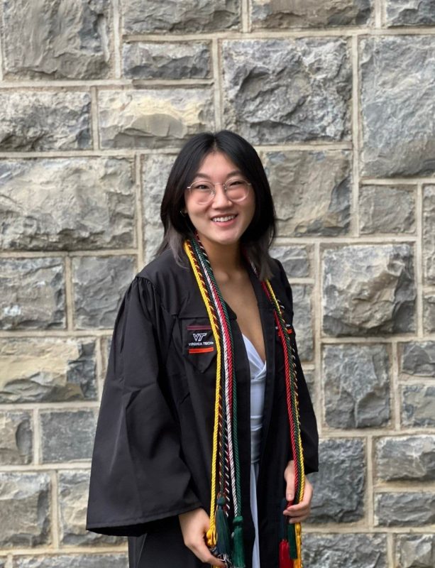 2023 SAS awardee Dana Dougherty in her graduation gown and cords. Hokiestone wall in the background.