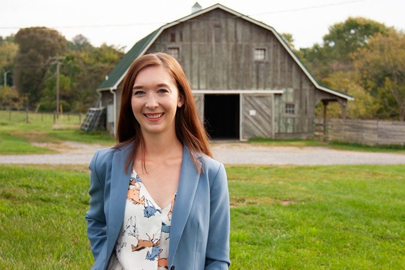 Photo of Madison Barshick with green roof barn in the background.
