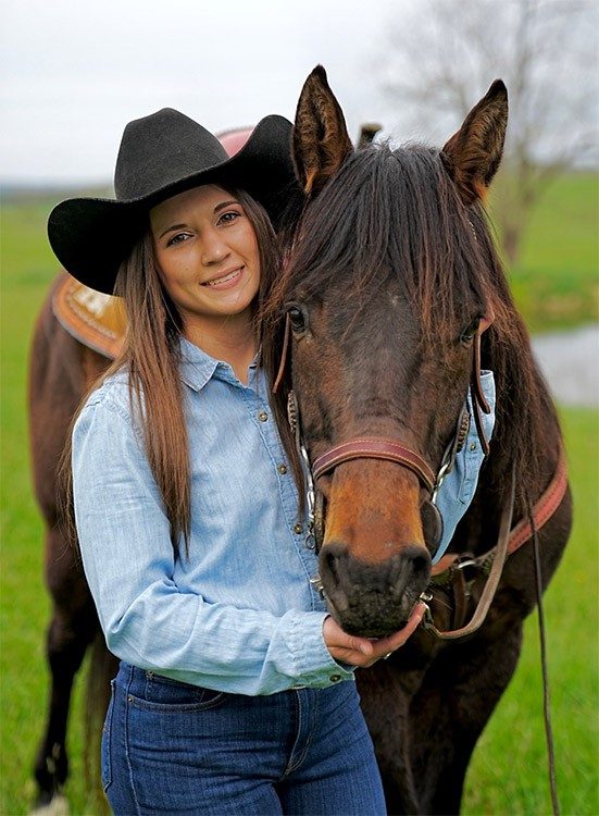 Undergraduate student wearing a black cowboy hat with her horse.
